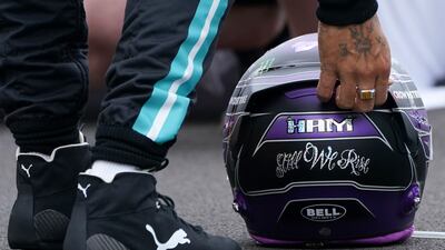 Mercedes driver Lewis Hamilton of Britain sets his helmet.