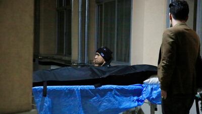 Afghan men sit near the body of a relative at a hospital in Kabul after a suicide bombing. AP