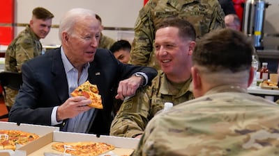 Mr Biden eats pizza as he talks to members of the 82nd Airborne Division at the G2A Arena in Jasionka, Poland. AP