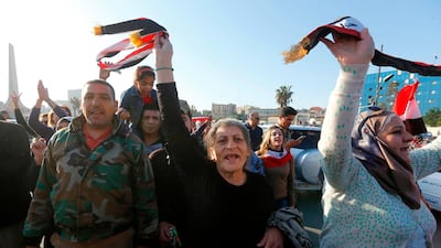Syrians wave the national flag as they gather at the Umayyad Square in Damascus, to condemn the strikes carried out by the US, Britain and France against the Syrian regime. Louai Beshara / AFP