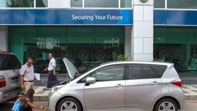 A car owner (standing) looks on while a private insurance company worker inspects a vehicle for insurance coverage, outside her office in Yangon. Romeo Gacad / AFP