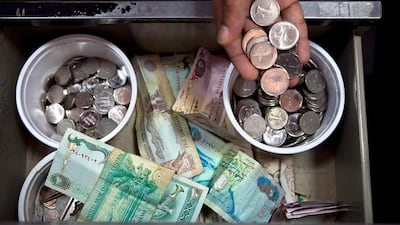 A store cashier receives payment from a customer at a local convenience store in Abu Dhabi. Silvia Razgova / The National