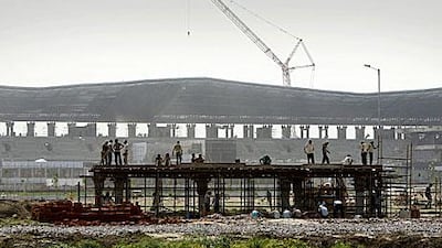 Construction workers a section of a building in the backdrop of the Sports City Motor Race Circuit under construction in Greater Noida, India.