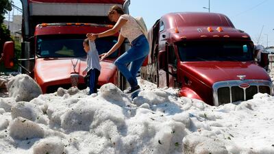 A woman and a child walk on hail in the eastern area of Guadalajara, Mexico. AFP
