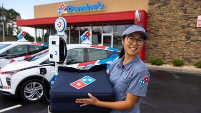 A Domino's worker prepares to get into a Chevy Bolt.