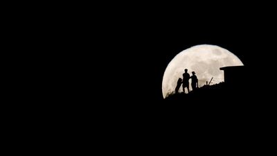 A couple next to a dog is seen on a mountain watching as the Supermoon rises above the Cruce de Arinaga, on the island of Gran Canaria, Spain. Reuters