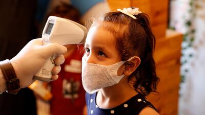 A girl has her body temperature checked while she arrives with her family at a beach side cafe in Gaza City, Monday, October 12. Adel Hana/ AP