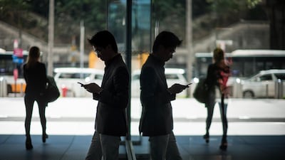 A man is reflected in a window while using a smartphone in Hong Kong, China. David Paul Morris / Bloomberg