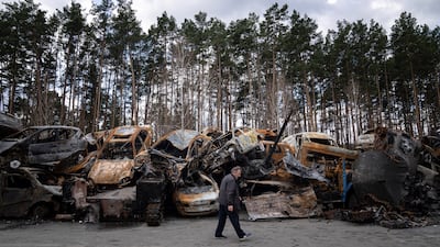 A man walks past a storage place for burned armed vehicles and cars, on the outskirts of Kyiv. AP