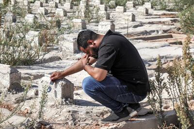 A family member grieving at the gravestone of one of the Derna victims. AFP