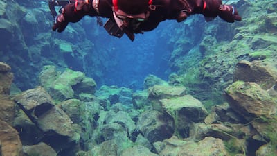 This handout picture taken underwater shows a snorkeller observing the fissure underwater on July 26, 2022 in Thingvellir, Iceland. - Located between the North American and Eurasian tectonic plates, at the bend of two continents, the Silfra Rift in Iceland is one of the most famous dive sites in the world, popular with tourists who venture into its icy waters every summer. (Photo by Thomas GOV / DIVE. IS / AFP) / RESTRICTED TO EDITORIAL USE - MANDATORY CREDIT "AFP PHOTO /Thomas GOV/DIVE. IS " - NO MARKETING - NO ADVERTISING CAMPAIGNS - DISTRIBUTED AS A SERVICE TO CLIENTS