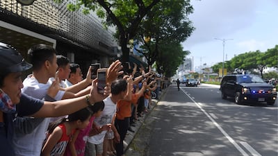 Vietnamese wave and take photos as the convoy transporting US president Donald Trump passes by. Hoang Dinh Nam / AFP Photo
