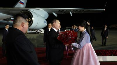 Mr Putin is welcomed with flowers as Mr Kim watches on. EPA / Sputnik / Kremlin pool