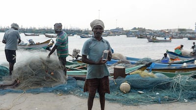 Indian fisherman Satish, 40, poses with his smartphone -- wrapped in plastic to keep it dry -- at Kasimedu harbour in Chennai. AFP