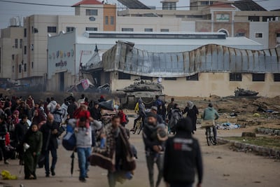 Internally displaced Palestinians walk past Israeli tanks in Gaza. EPA