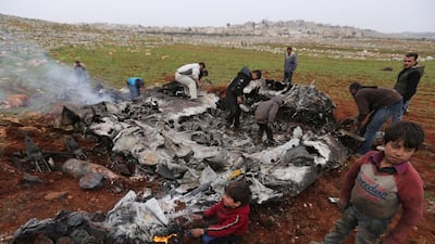 Syrians gather around a wreckage of a government military helicopter that was shot down in the countryside west of the city of Aleppo, Friday, Feb. 14, 2020. AP