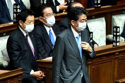 Shinzo Abe, right, walks past Prime Minister Fumio Kishida, centre, during a parliament session in Tokyo earlier in the month. AFP