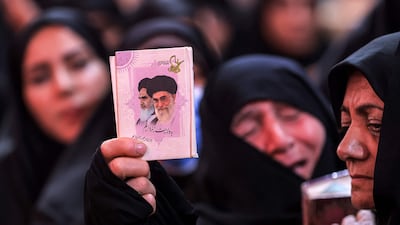 A woman holds a picture of Iran's late supreme leaders Ali Khamenei and Ruhollah Khomeini during mourning rituals at the Shrine of Imam Hussein in Karbala on June 25. AFP