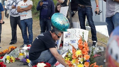 A mourner looks at flowers and memorials at the car crash site that killed actor Paul Walker and another man, north of Los Angeles Nick Ut / AP Photo