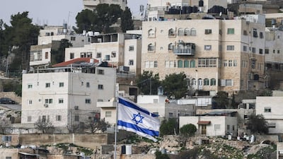 An Israeli flag above the Beit Romano settlement against a backdrop of Palestinian homes in the West Bank city of Hebron. AFP