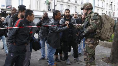 A French soldier checks the identity papers of a man in the area where shots were exchanged in Saint-Denis, France. Jacky Naegelen / Reuters