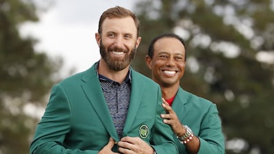 Dustin Johnson of the US is presented his green jacket by defending champion Tiger Woods. EPA