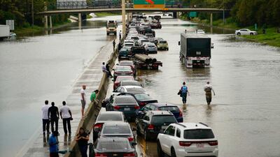 People wait outside of their stranded vehicles along Interstate 10 westbound at T.C Jester, Thursday, Sept. 19, 2019. The freeway is closed because of high water east bound on the freeway. (Mark Mulligan/Houston Chronicle via AP)