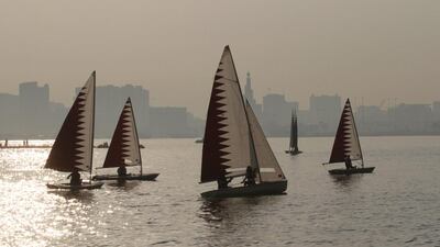 Members of the Qatari armed forces ride on sail boats.