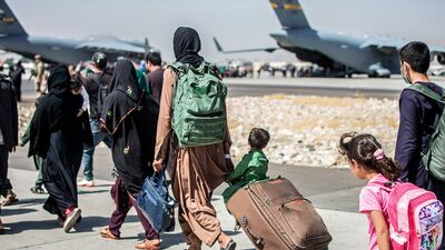 Families walk towards their flight during ongoing evacuations at Hamid Karzai International Airport, Kabul, Afghanistan. AP