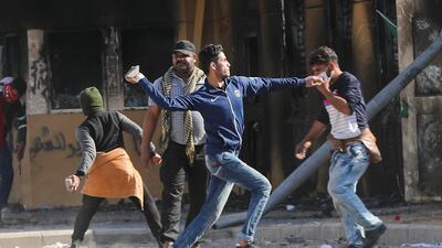 Militia fighters throw stones towards the US embassy during a demonstration condemning US air strikes on bases belonging to Kataib Hezbollah in Iraq. Reuters