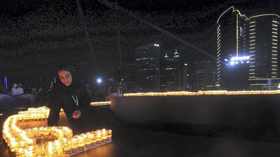 A participant lights candles during the Earth Hour Walk at the Marasi promenade in Dubai. Satish Kumar / The National