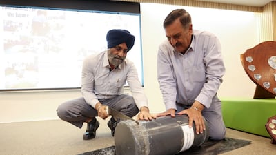 Afsar Khan, operations assistant, and Sharanjit Singh, site supervisor, open a time capsule buried by pupils in 1999. Chris Whiteoak / The National