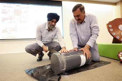 Afsar Khan, operations assistant, and Sharanjit Singh, site supervisor, open the time capsule at Sharjah English School. Chris Whiteoak / The National