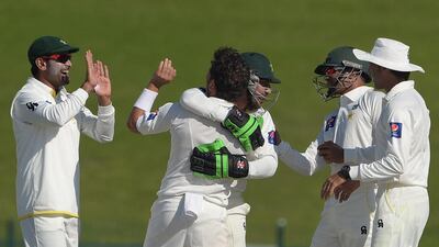 Pakistani cricketers celebrate after the dismissal of New Zealand cricket captain Brendon McCullum during the fourth day of the first Test match between Pakistan and New Zealand at the Zayed International Cricket Stadium in Abu Dhabi. Aamir Qureshi / AFP