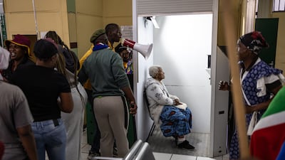 Protesters chant as an elderly woman waits for her identity card photo at the Department of Home Affairs offices during a demonstration calling for the removal of undocumented immigrants in Alexandra township, South Africa. AFP