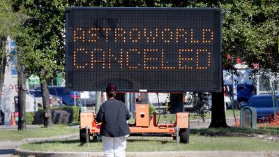 A pedestrian crosses Main Street in front of a sign announcing the cancellation of Astroworld. AP