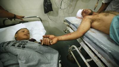 A wounded Palestinian boy and his father hold hands at a hospital after their house was blown up by an Israeli air strike in Gaza early on October 11, killing a Palestinian woman and her young daughter. REUTERS/Mohammed Salem