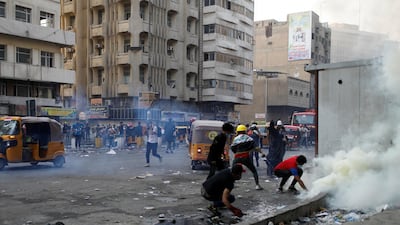 Demonstrators try to put out a tear gas canister during an anti-government protests in Baghdad, Iraq. Reuters