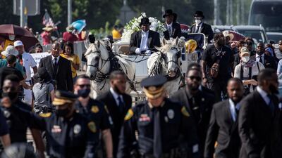 A row of police officers walk ahead of the horse-drawn carriage coffin of George Floyd, whose death in Minneapolis police custody has sparked nationwide protests against racial inequality. Reuters