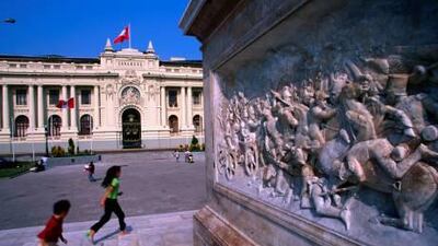 Children run past the Simon Bolivar monument in Piazza Bolivar, Lima.
