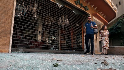 People walk on glass from broken windows littering a street after the violence. AP