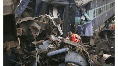 A rescue worker searches through the wreckage of a passenger train which derailed near Fatehpur, Uttar Pradesh. The death toll climbed to 80 yesterday, with more than 350 injured in one of the worst rail disasters to hit the country's troubled rail network in years. Jitendra Prakash / Reuters