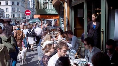 People sit in a cafe as they enjoy the sun in Montmartre, Paris. The French have a 35-hour work week introduced in 2000. Fred Dufour / AFP