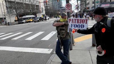 Stickers reading "Guns save lives" are put on a food drive sign as armed people stand on a corner near the Virginia State Capitol while a caravan of cars drives by in support of second amendment rights, in Richmond, Virginia, U.S. Reuters