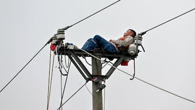 An electricity worker rests as he works on a power line in Hanoi, Vietnam. AFP