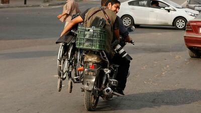Moamen Qreiqea holds his wheelchair as he rides on a motorcycle.