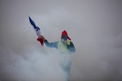 A demonstrator holds a French flag as he walks amid the tear gas during a protest of Yellow vests (Gilets jaunes) against rising oil prices and living costs, on December 1, 2018 in Paris. AFP
