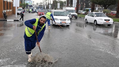 Egyptian municipal workers try to clear flood water from a street during rain shower in Cairo. EPA