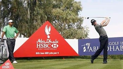 Tiger Woods, left, watches Rory McIlroy tee off on the sixth hole during the first round of the Abu Dhabi HSBC Golf Championship. Jeff Topping / The National
