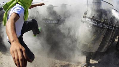 An activist kicks the shields of the military police officers during a demonstration in the military zone of the 27th infantry battalion in Iguala, Guerrero. Jorge Dan Lopez / Reuters